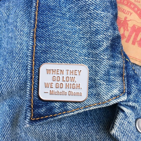 "When they go low, we go high" enamel pin